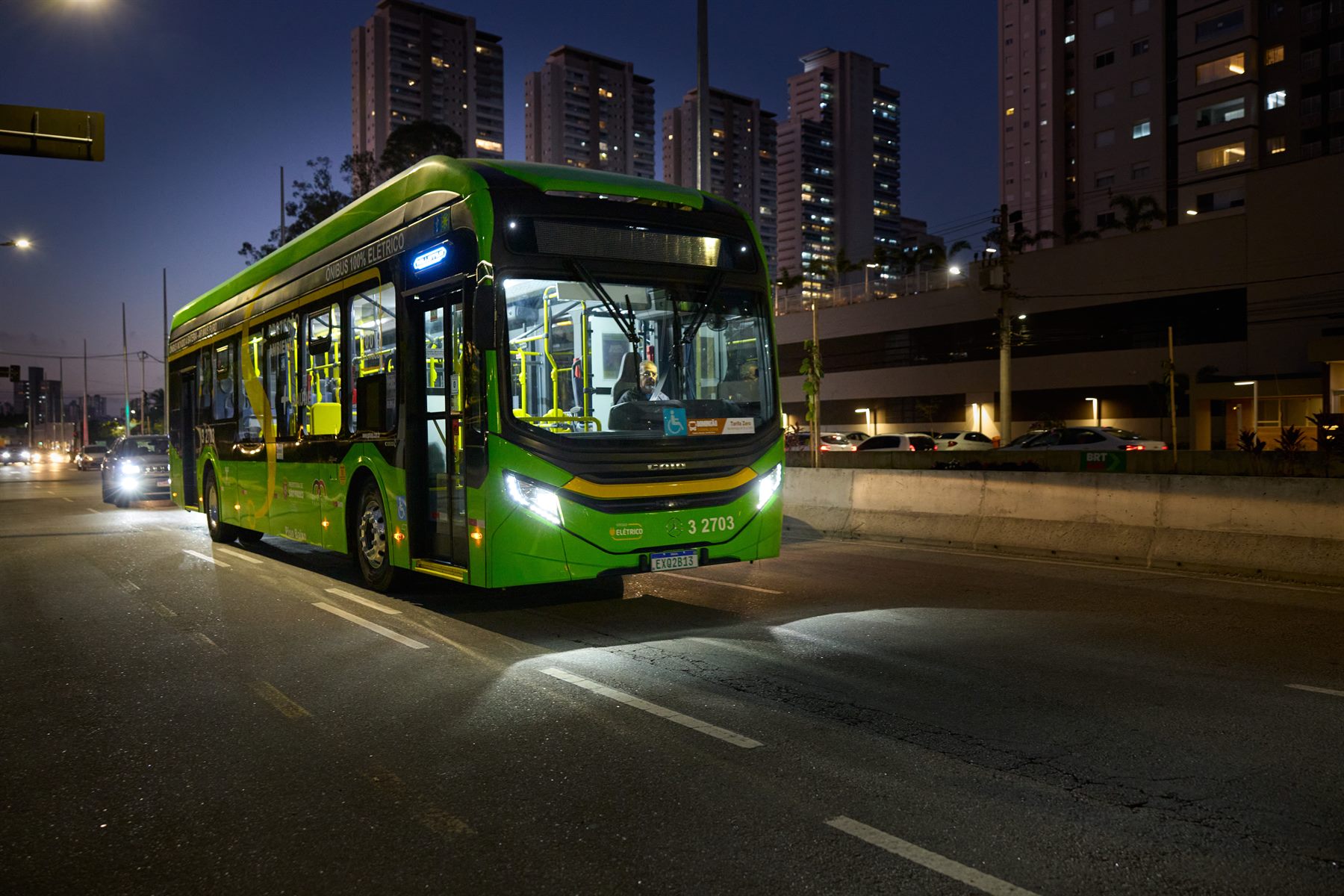 Ônibus Mercedes-Benz 100% elétrico da frota de São Paulo circulando em uma avenida ao anoitecer.